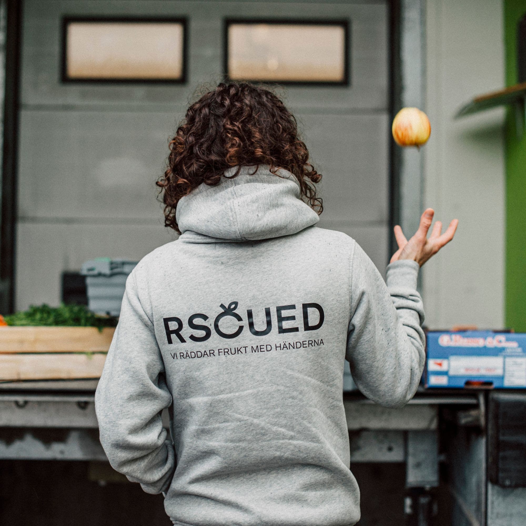 Tjej med rscued tröja som kastar upp ett äpple i luften