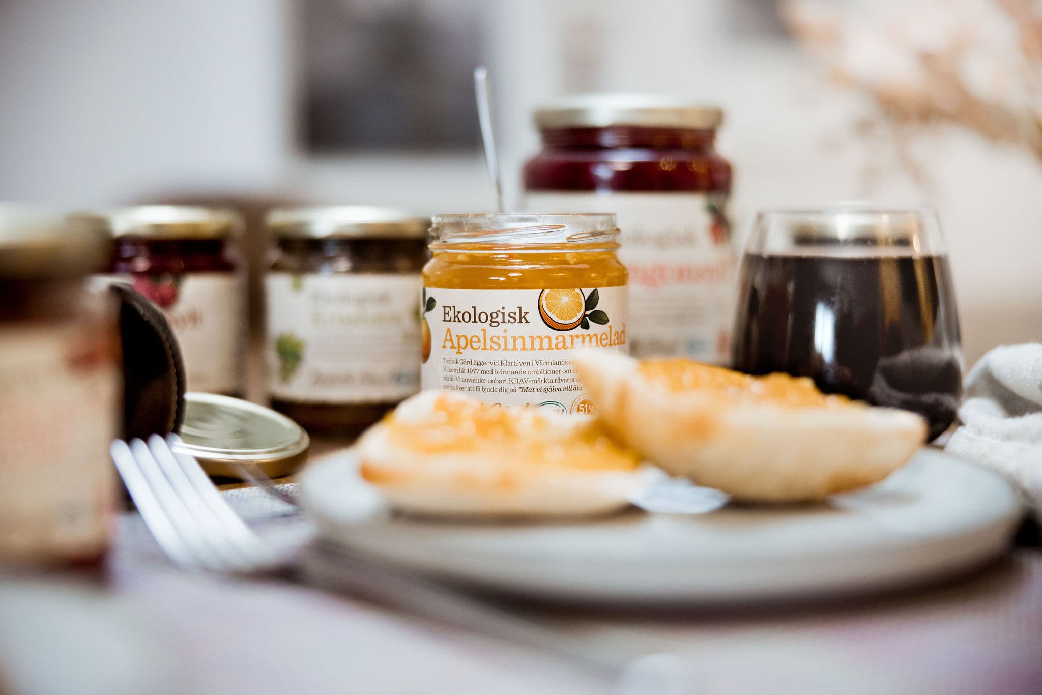 Marmelad burk snett från sidan med rostat bröd på tallrik framför